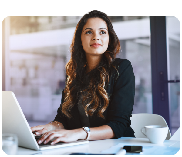 woman typing on a laptop and looking off into the distance 