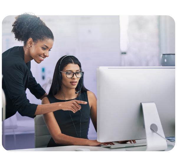 Woman smiling and pointing at a computer another woman is working on