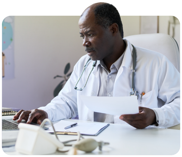 doctor looking at his computer while holding a piece of paper